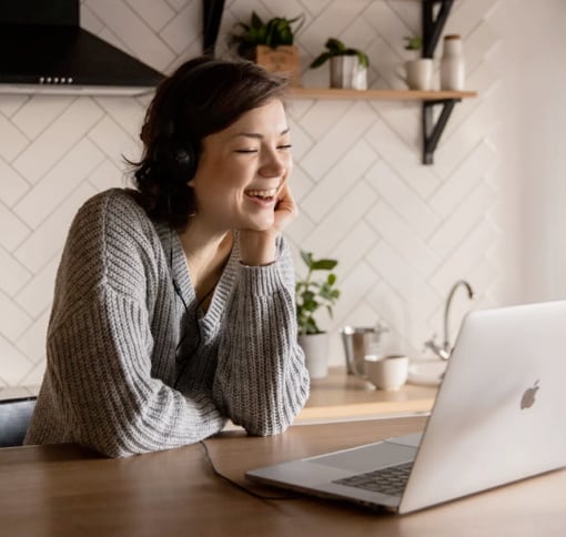 A cheery woman attending a video call on her MacBook