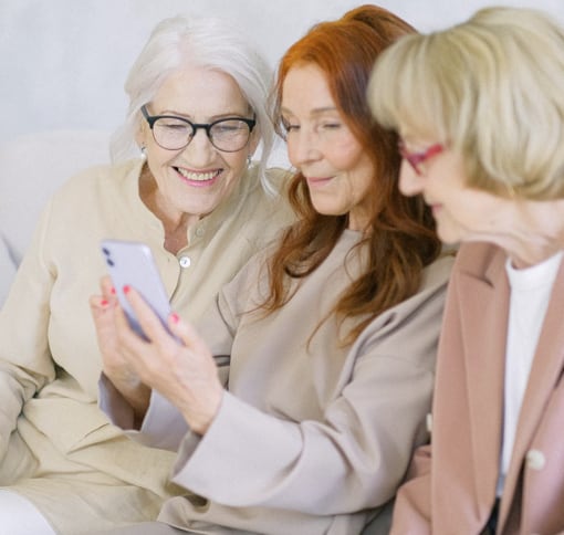 A group of 3 elderly women taking a video call on a mobile phone